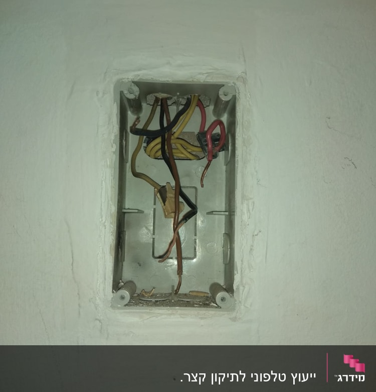 חוטי חשמל צבעוניים בקופסת חיבורים בקיר